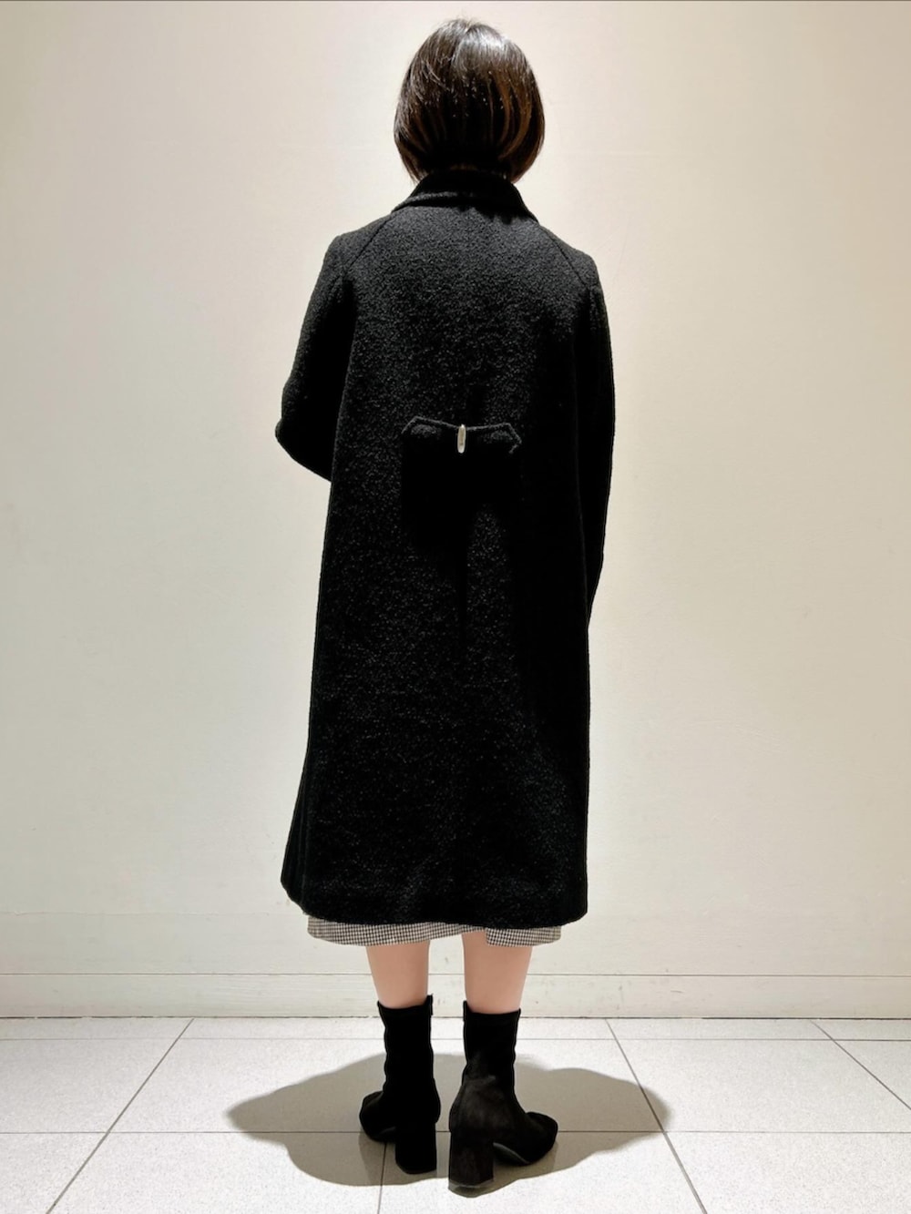 ブラック系のステンカラーコートを着用したレディースの秋コーディネートの3枚目の写真