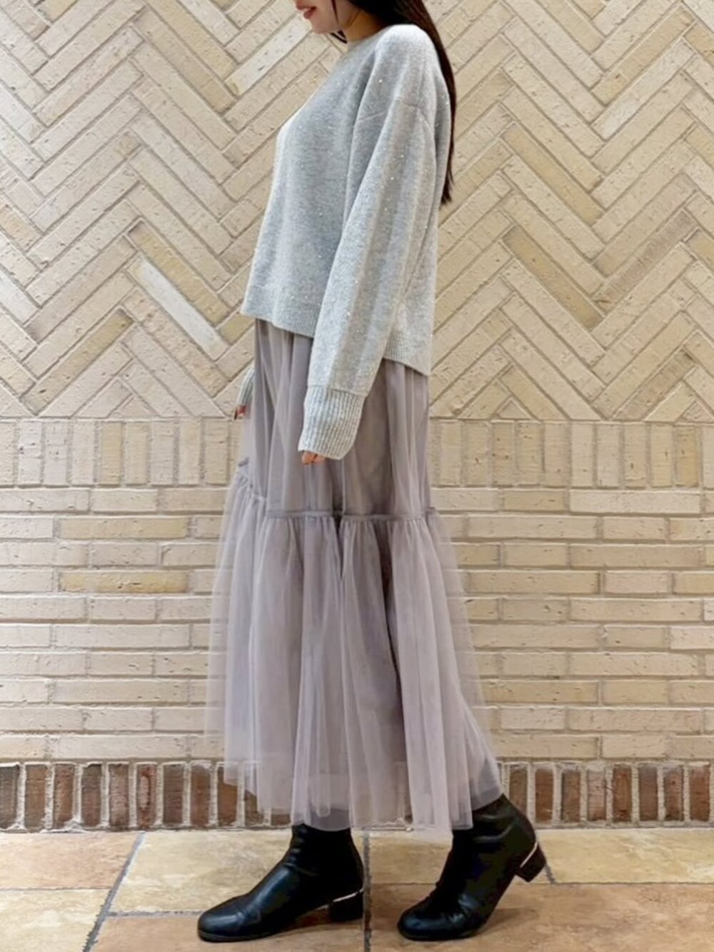 グレー系のスカート、グレー系のニット/セーターを着用したレディースの冬コーディネートの2枚目の写真