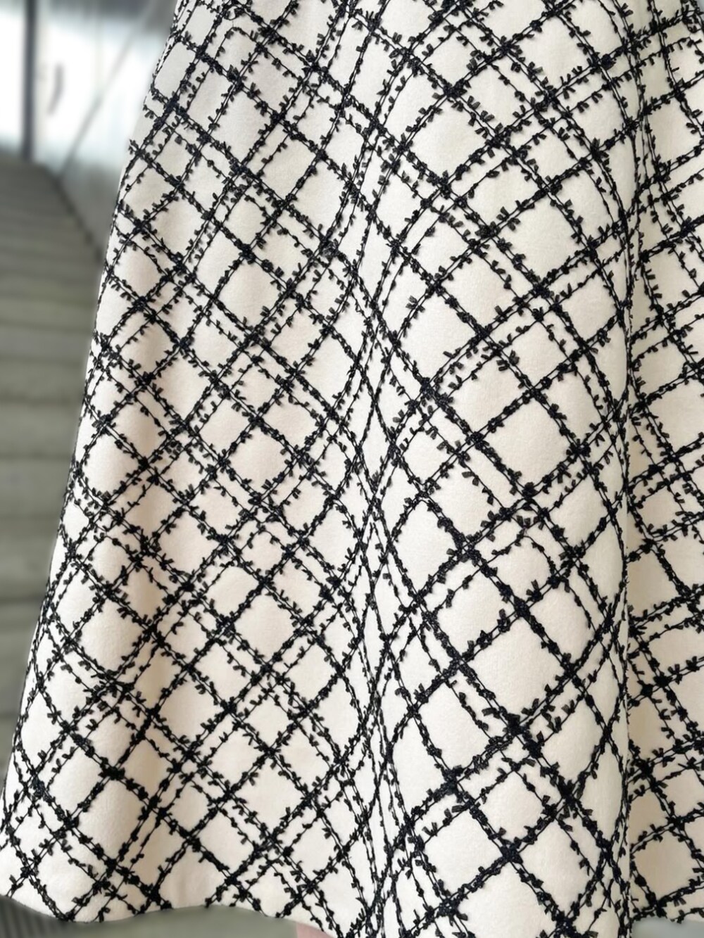 ブラック系のニット/セーター、ホワイト系のスカートを着用したレディースの秋コーディネートの4枚目の写真