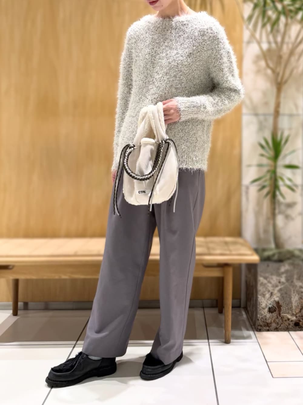 グレー系のスラックス、ホワイト系のニット/セーターを着用したレディースの冬コーディネートの4枚目の写真