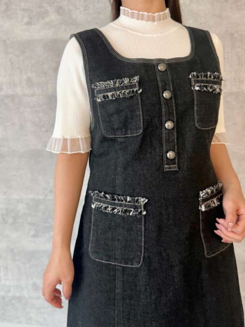 ブルー系のジャンパースカート、ホワイト系のニット/セーターを着用したレディースの春コーディネートの2枚目の写真