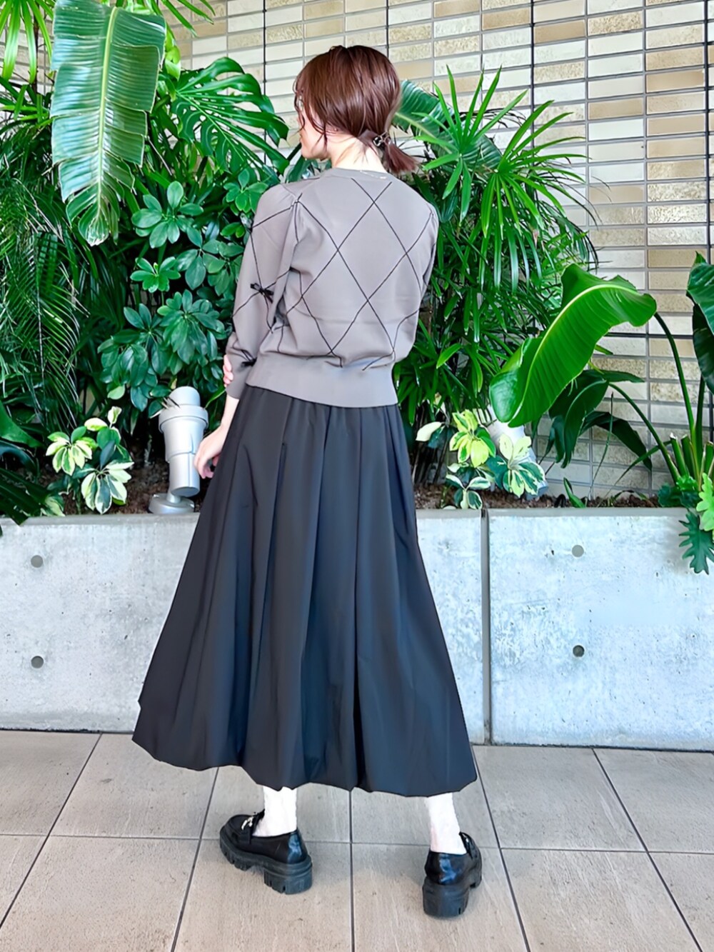 ブラック系のスカート、グレー系のニット/セーターを着用したレディースの秋コーディネートの2枚目の写真