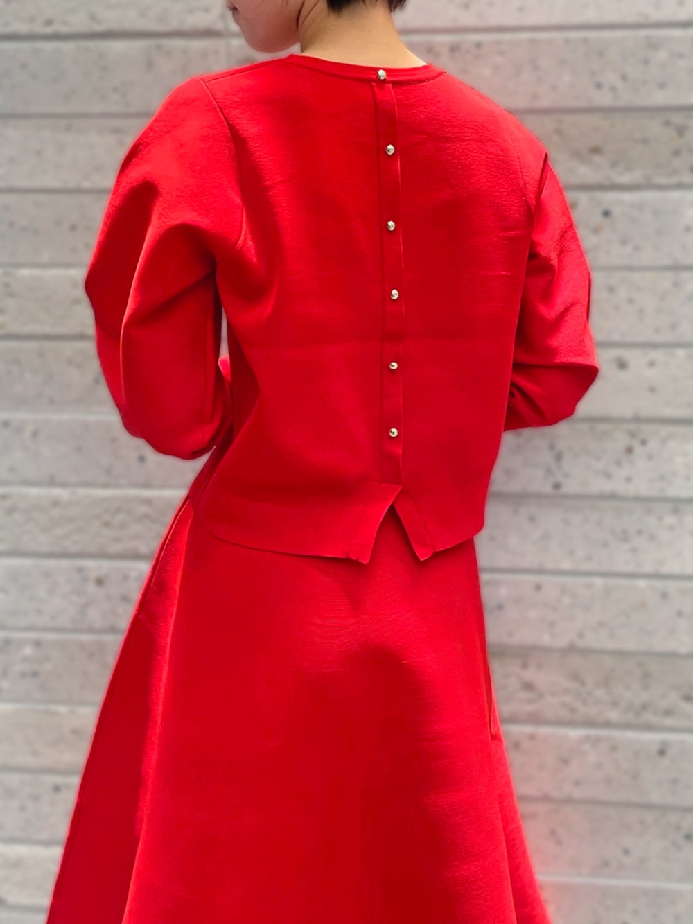 レッド系のニット/セーター、レッド系のスカートを着用したレディースの秋コーディネートの3枚目の写真