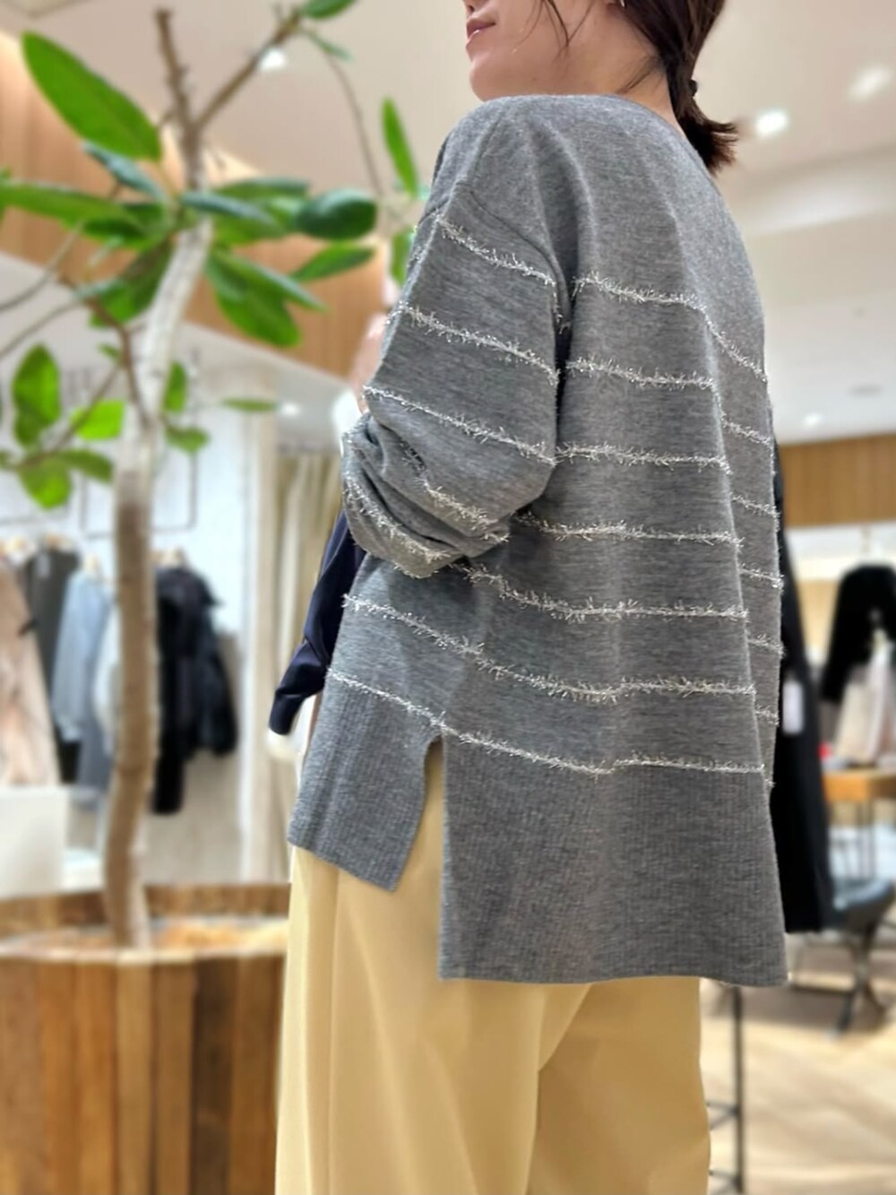 イエロー系のスラックス、グレー系のニット/セーターを着用したレディースの秋コーディネートの2枚目の写真