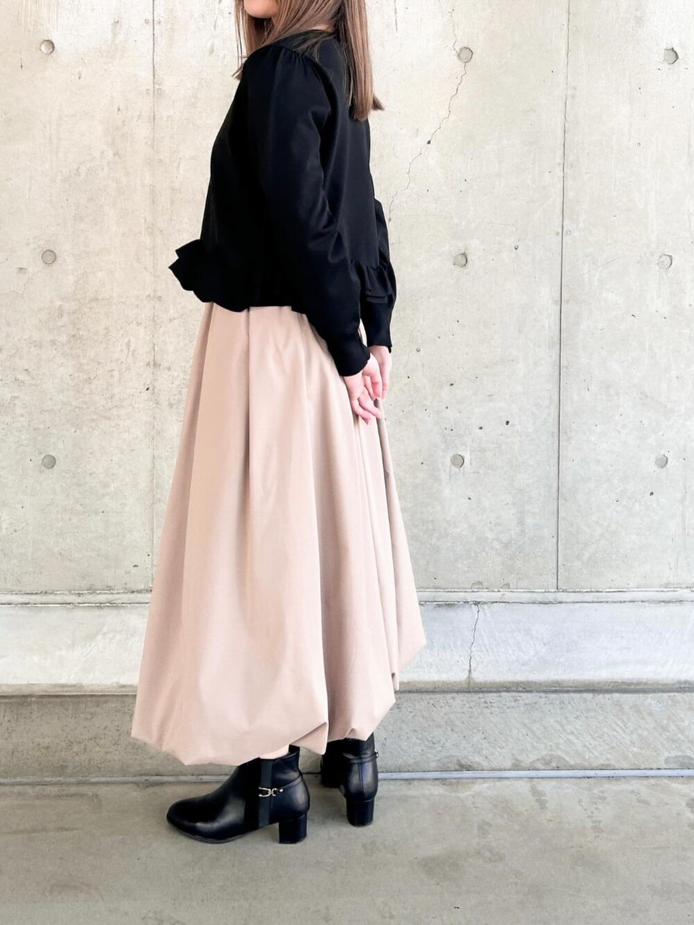 イエロー系のスカート、ブラック系のニット/セーターを着用したレディースの冬コーディネートの2枚目の写真