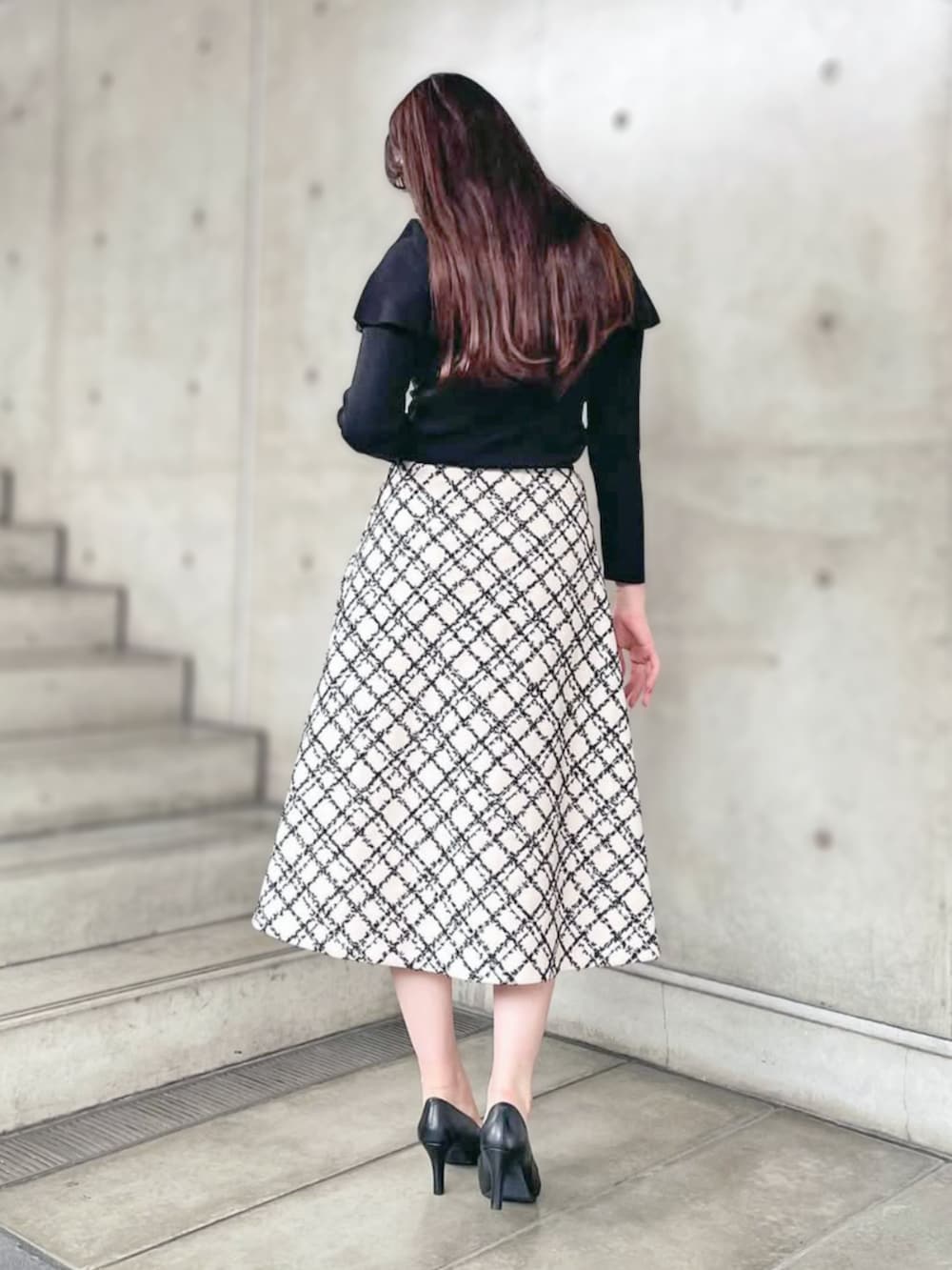 ブラック系のニット/セーター、ホワイト系のスカートを着用したレディースの秋コーディネートの2枚目の写真