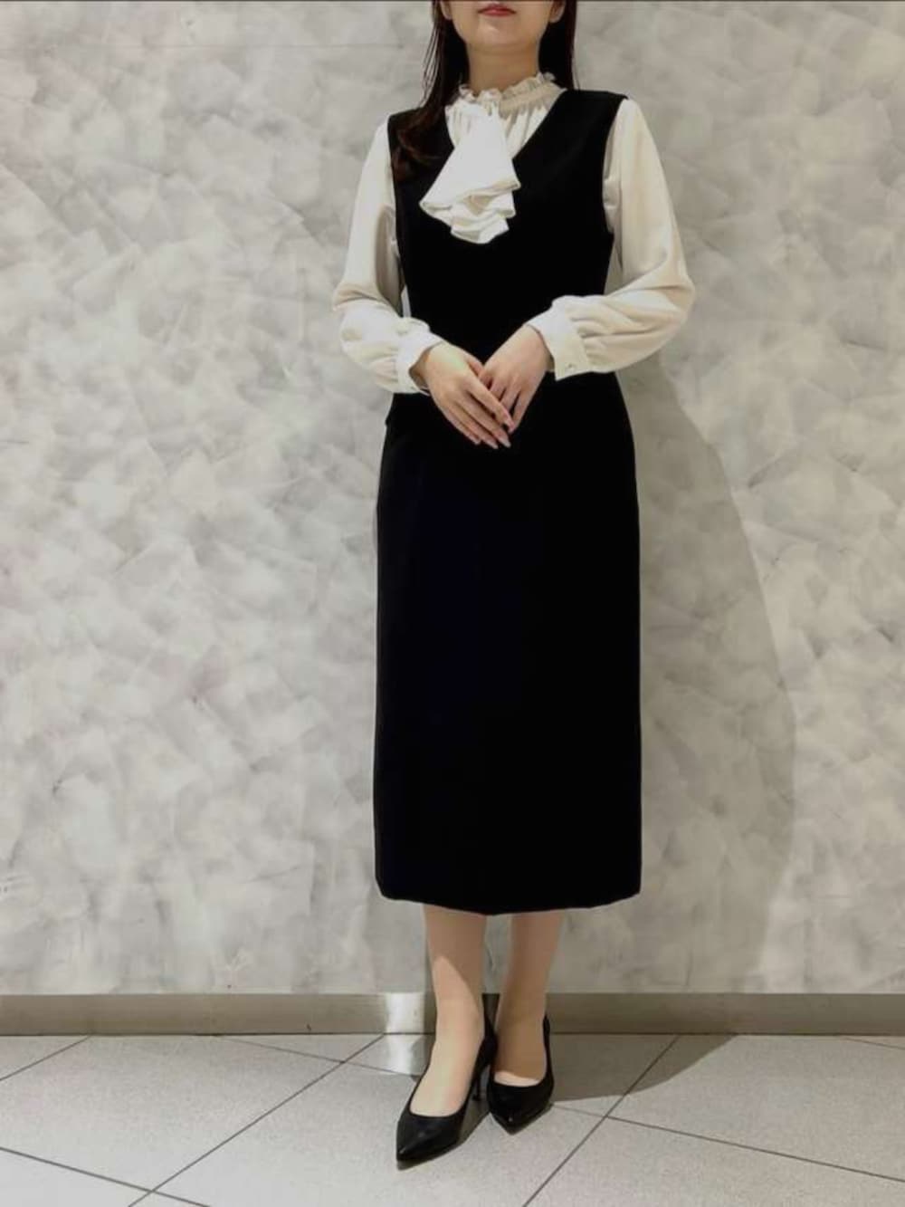 ホワイト系のシャツ/ブラウス、ブラック系のジャンパースカート、ブラック系のテーラードジャケットを着用したレディースの春コーディネートの2枚目の写真