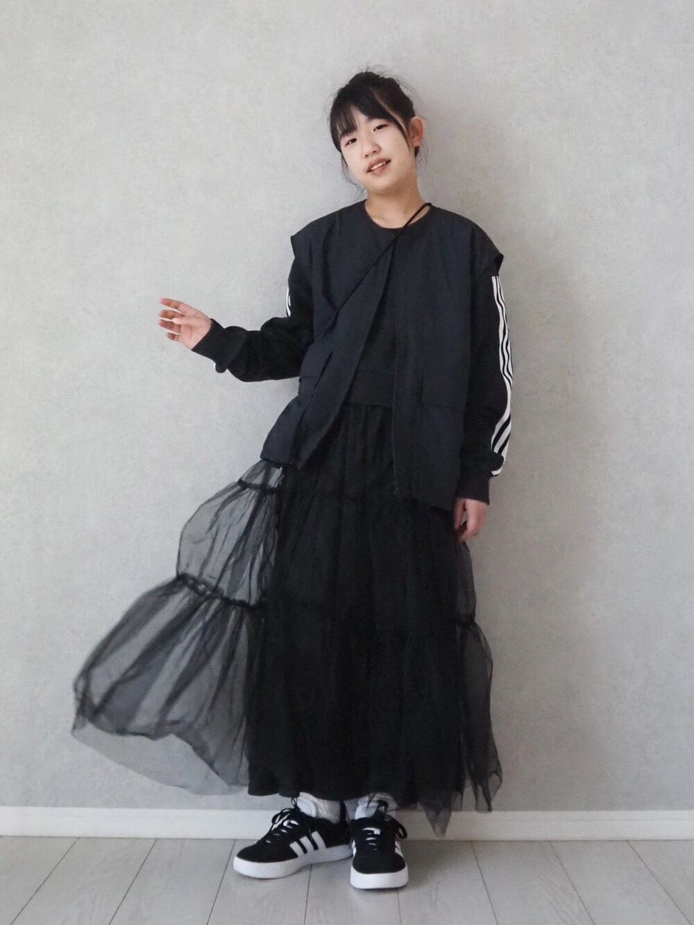 ブラック系のスカート、ブラック系のベストを着用したキッズの春コーディネートの2枚目の写真