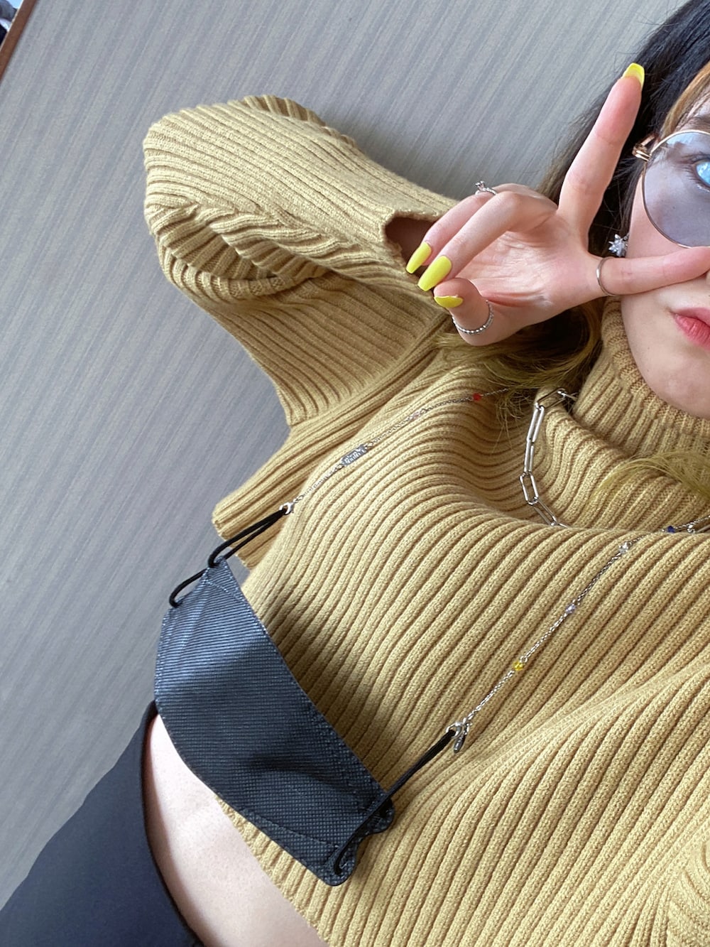 ブラック系のスカート、イエロー系のニット/セーター、ブラック系のブーツを着用したレディースの秋コーディネートの2枚目の写真