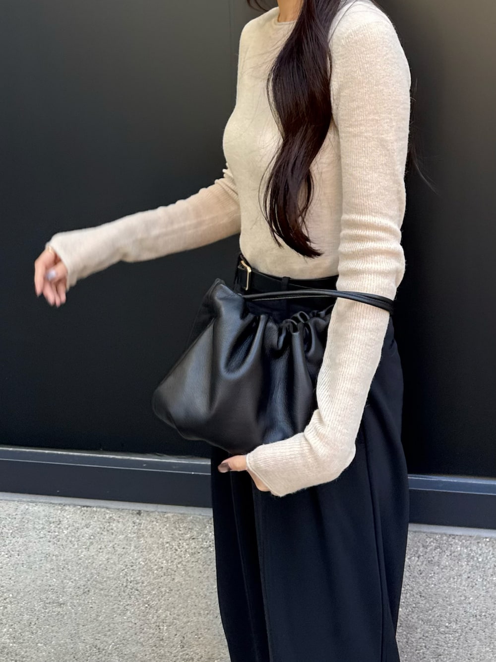 ブラック系のショルダーバッグ、ブラック系のスラックス、ベージュ系のTシャツ/カットソーを着用したレディースの冬コーディネートの2枚目の写真