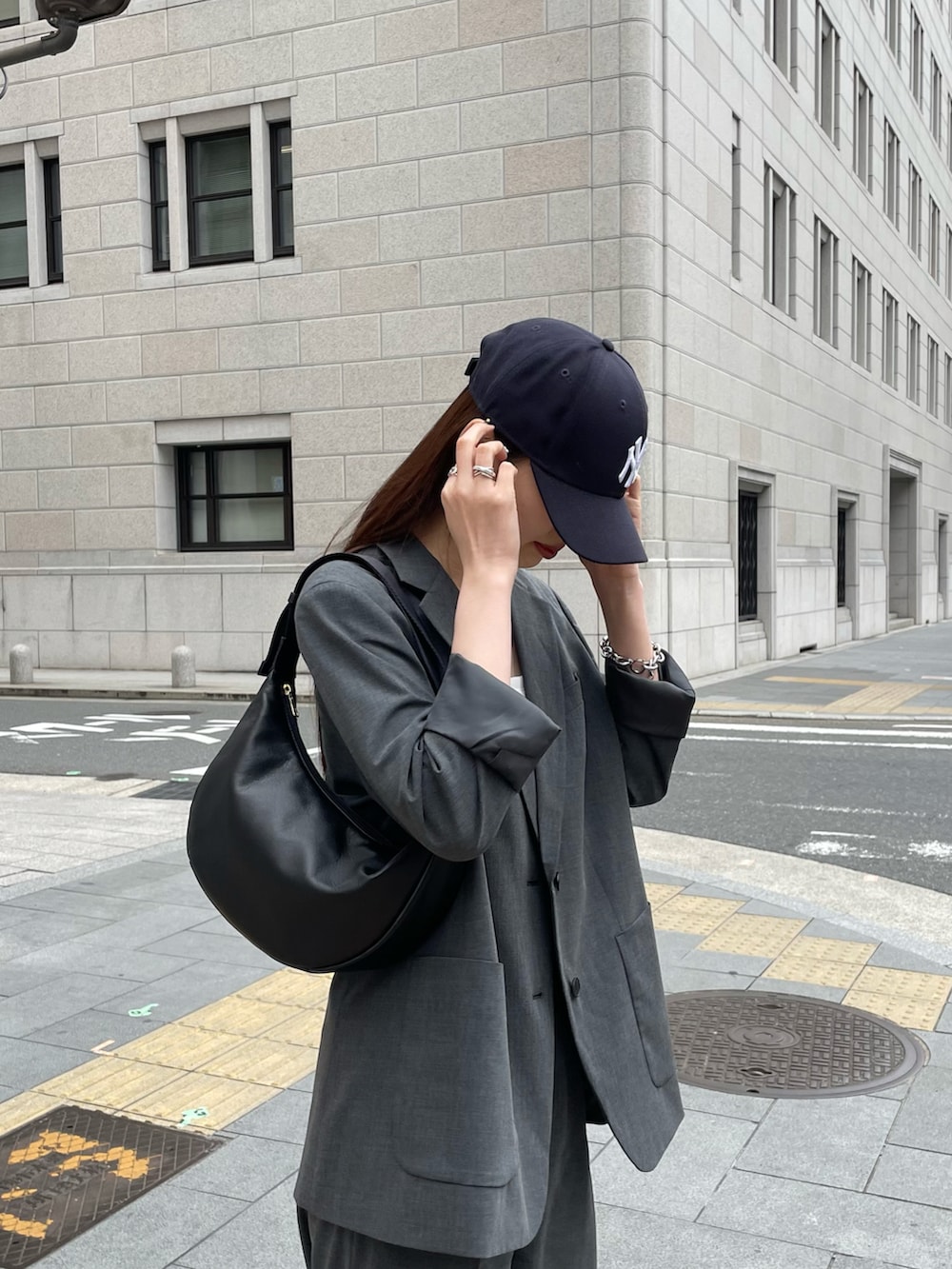 ブラック系のショルダーバッグ、グレー系のスラックス、グレー系のテーラードジャケットを着用したレディースの春コーディネートの2枚目の写真