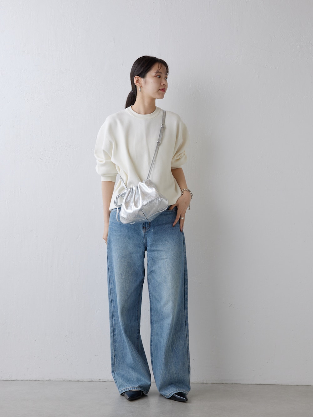 シルバー系のショルダーバッグ、ブルー系のデニムパンツ、ホワイト系のニット/セーターを着用したレディースの秋コーディネートの3枚目の写真
