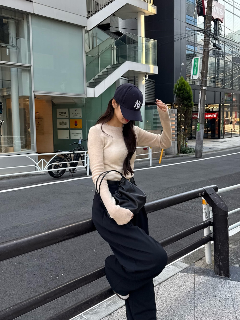 ブラック系のショルダーバッグ、ブラック系のスラックス、ベージュ系のTシャツ/カットソーを着用したレディースの冬コーディネートの3枚目の写真