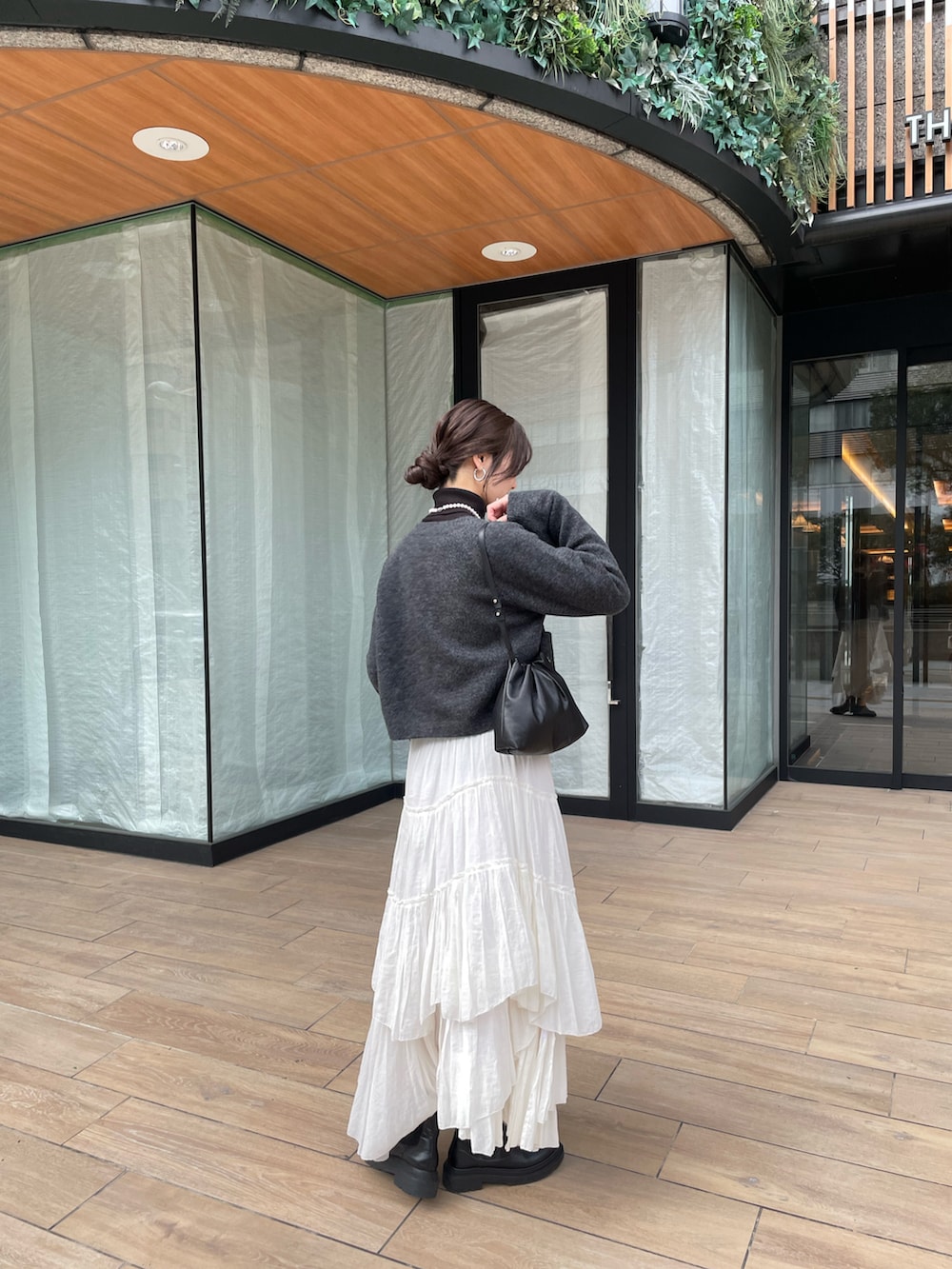 ブラック系のショルダーバッグ、ホワイト系のスカートを着用したレディースの冬コーディネートの2枚目の写真