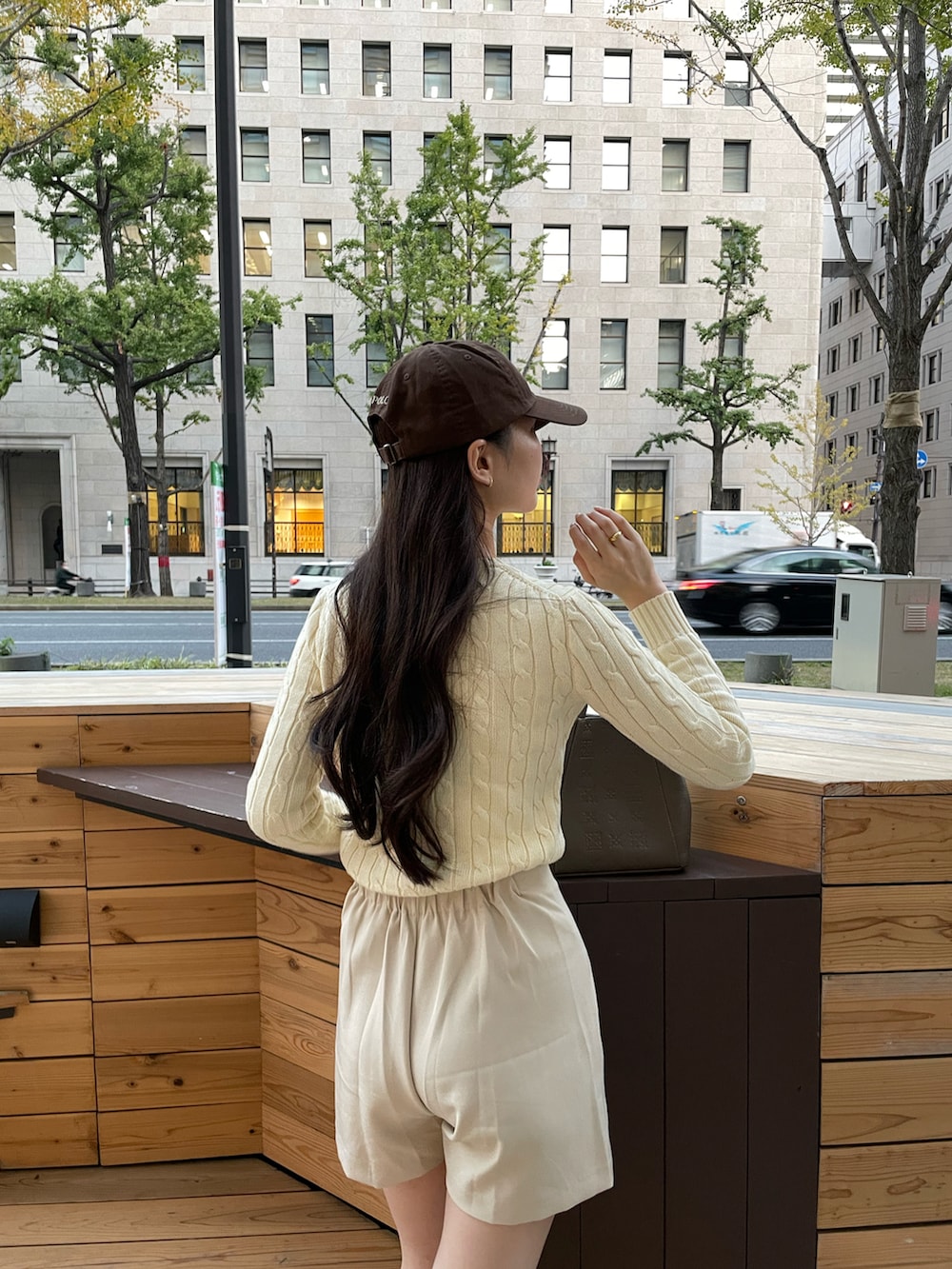 ブラウン系のショルダーバッグ、ホワイト系のスカート、ベージュ系のニット/セーターを着用したレディースの冬コーディネートの2枚目の写真