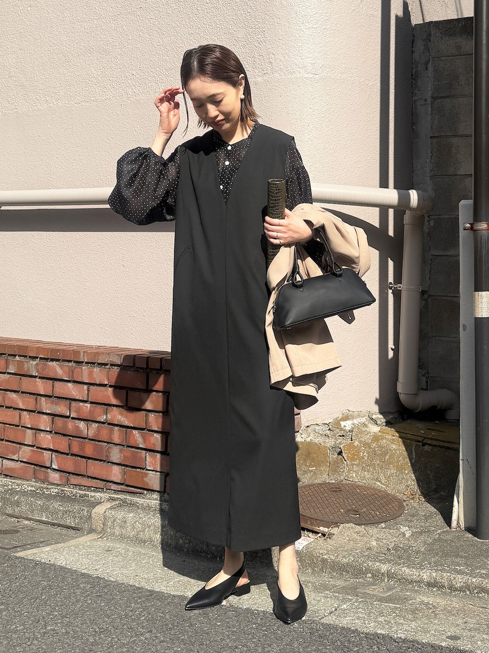 ベージュ系のトレンチコート、ブラック系のワンピース、ブラック系のシャツ/ブラウスを着用したレディースの春コーディネートの2枚目の写真