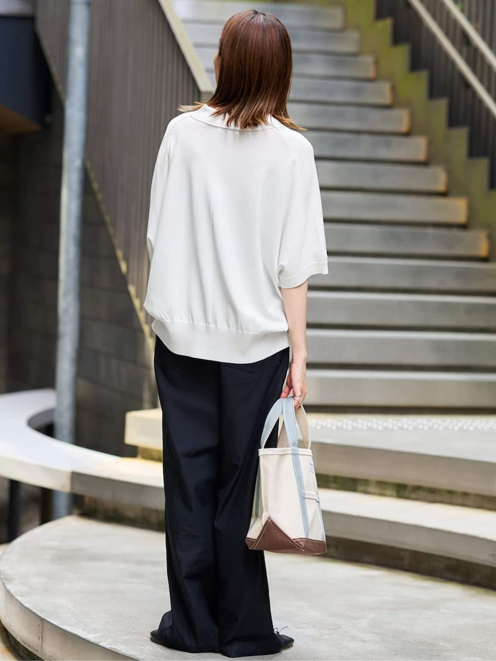 ブラック系のカーゴパンツ、ホワイト系のニット/セーター、ホワイト系のトートバッグを着用したレディースの夏コーディネートの3枚目の写真