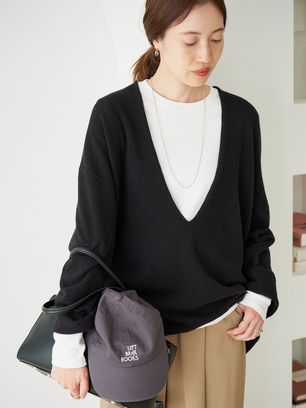 ベージュ系のスラックス、グレー系のTシャツ/カットソー、ブラック系のニット/セーターを着用したレディースの秋コーディネートの3枚目の写真