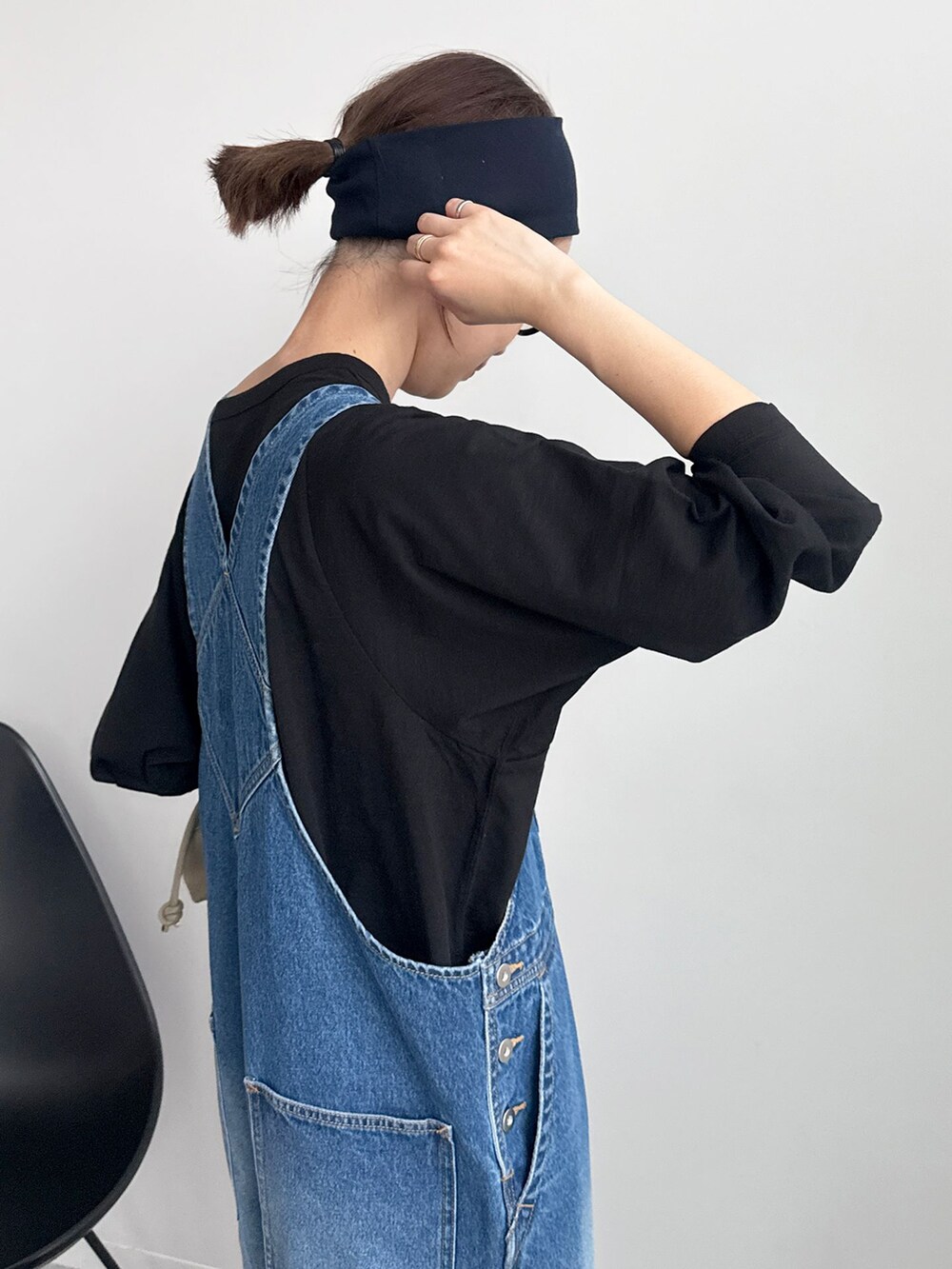 ブラック系のTシャツ/カットソー、ベージュ系のクラッチバッグ、ホワイト系のスニーカーを着用したレディースの冬コーディネートの4枚目の写真