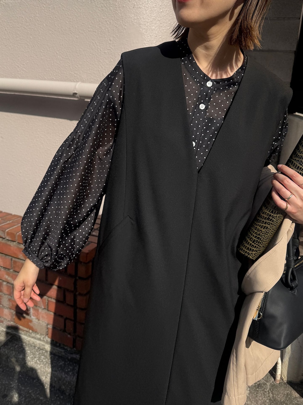 ベージュ系のトレンチコート、ブラック系のワンピース、ブラック系のシャツ/ブラウスを着用したレディースの春コーディネートの6枚目の写真