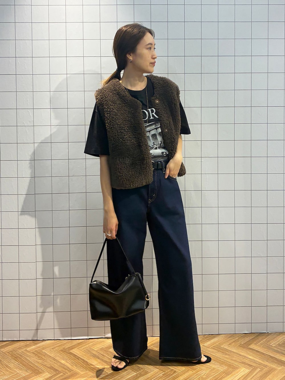 ブルー系のデニムパンツ、ブラック系のTシャツ/カットソー、ブラウン系のベストを着用したレディースの夏コーディネートの3枚目の写真