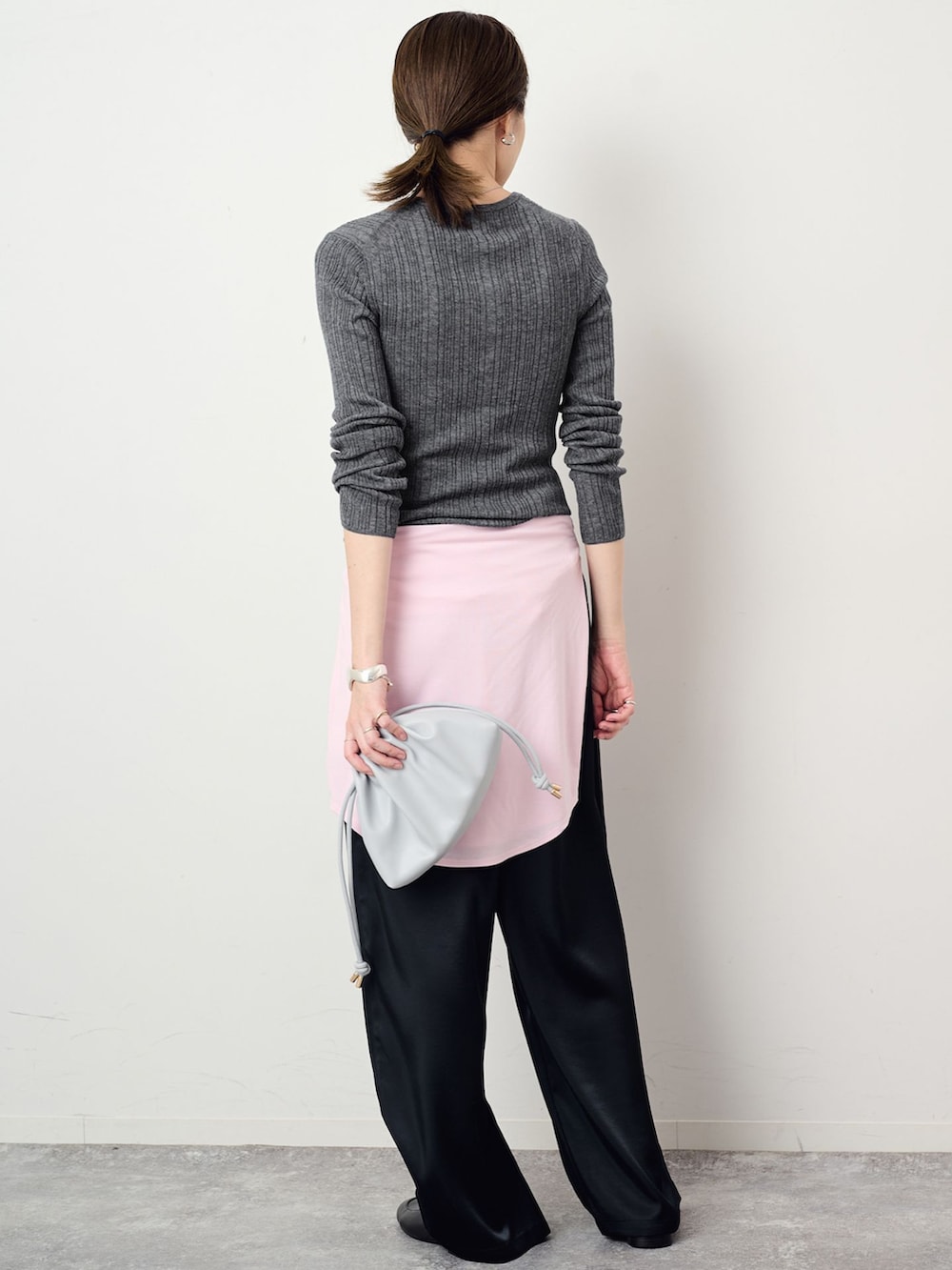 ブラック系のその他パンツ、グレー系のニット/セーター、ブルー系のクラッチバッグを着用したレディースの夏コーディネートの3枚目の写真
