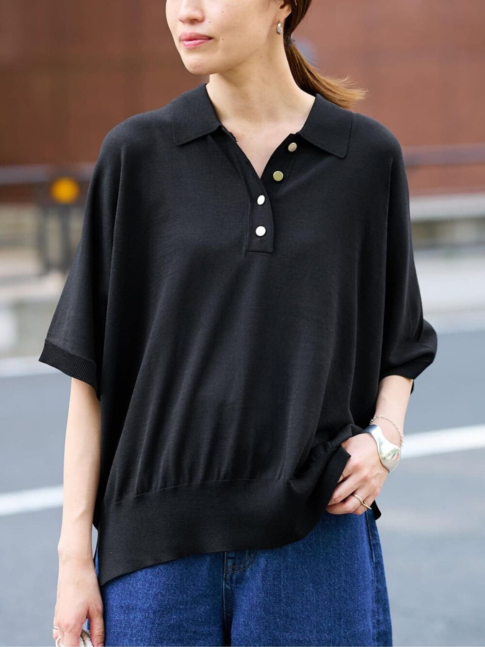 ブルー系のデニムパンツ、ブラック系のニット/セーター、ホワイト系のトートバッグを着用したレディースの夏コーディネートの4枚目の写真