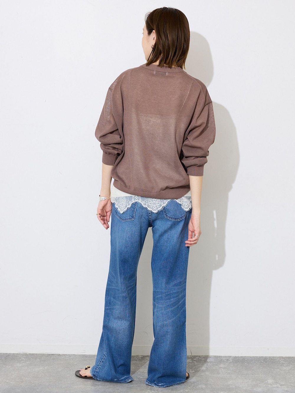 ブルー系のデニムパンツ、ホワイト系のキャミソール、ブラウン系のカーディガン/ボレロを着用したレディースの夏コーディネートの3枚目の写真