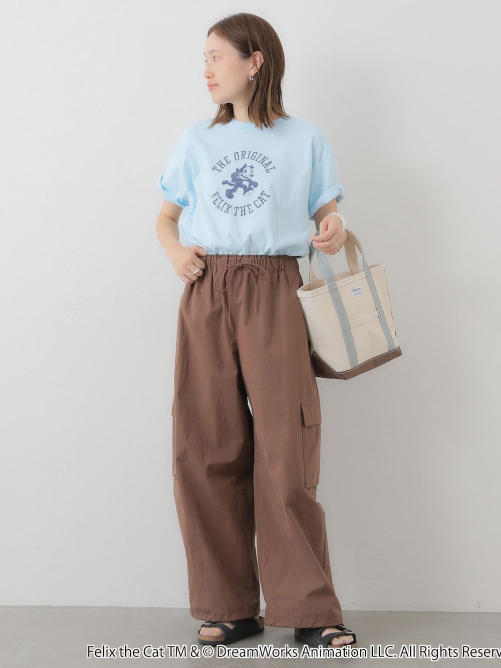 ブラウン系のカーゴパンツ、ブルー系のTシャツ/カットソー、ホワイト系のトートバッグを着用したレディースの夏コーディネートの2枚目の写真