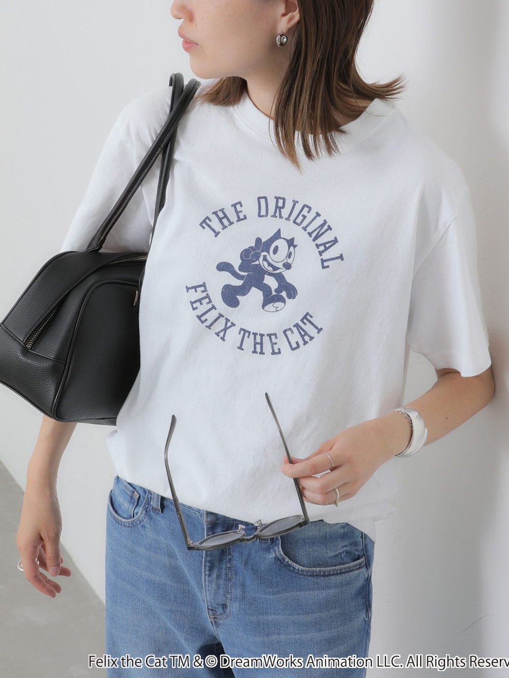 ブルー系のデニムパンツ、ホワイト系のTシャツ/カットソー、ブラック系のボストンバッグを着用したレディースの夏コーディネートの6枚目の写真