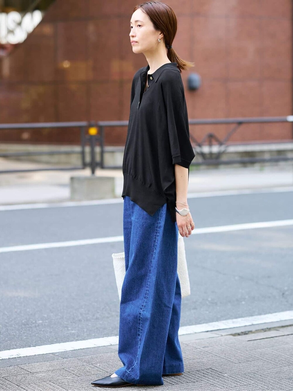 ブルー系のデニムパンツ、ブラック系のニット/セーター、ホワイト系のトートバッグを着用したレディースの夏コーディネートの2枚目の写真