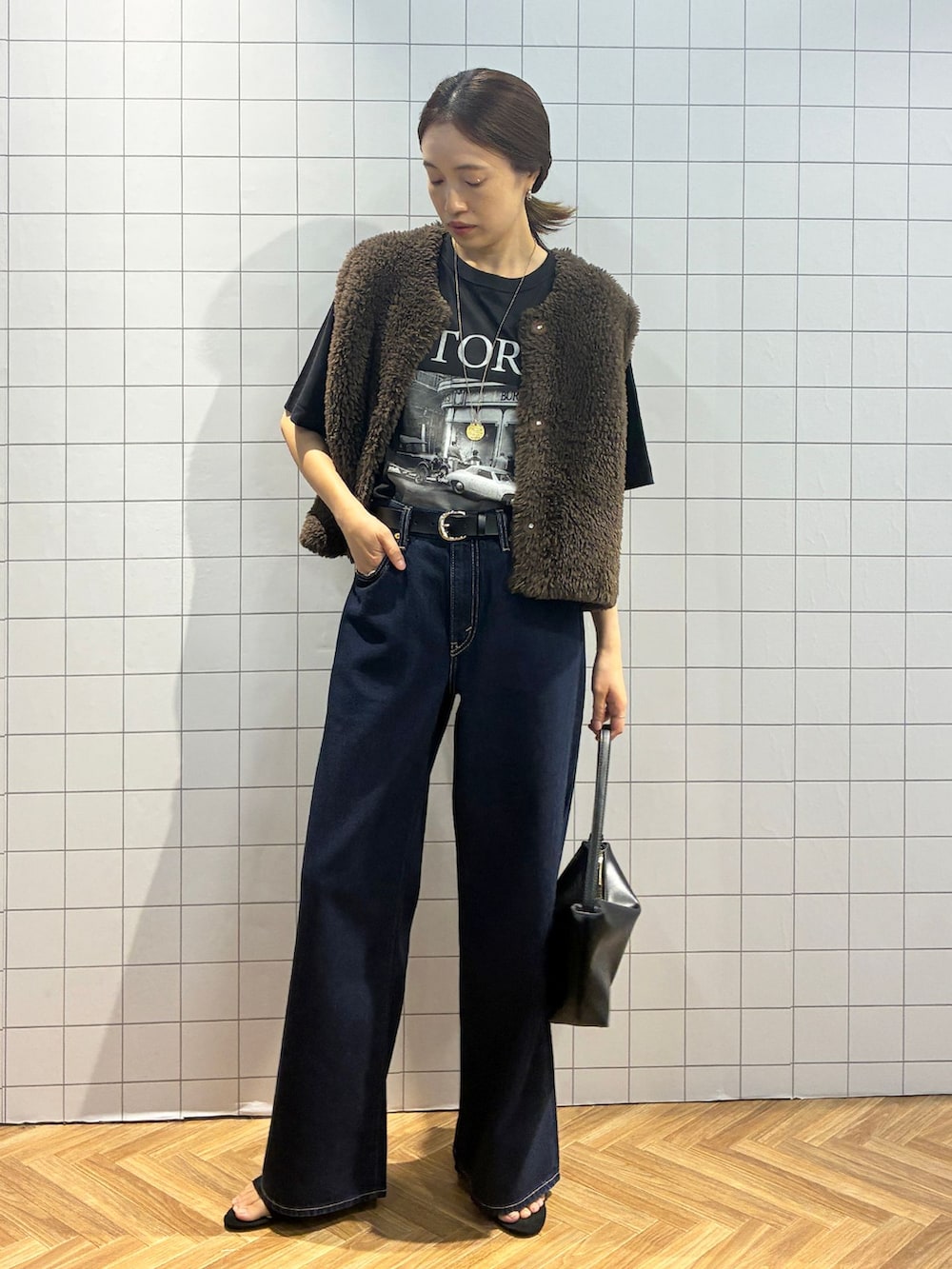 ブルー系のデニムパンツ、ブラック系のTシャツ/カットソー、ブラウン系のベストを着用したレディースの夏コーディネートの2枚目の写真