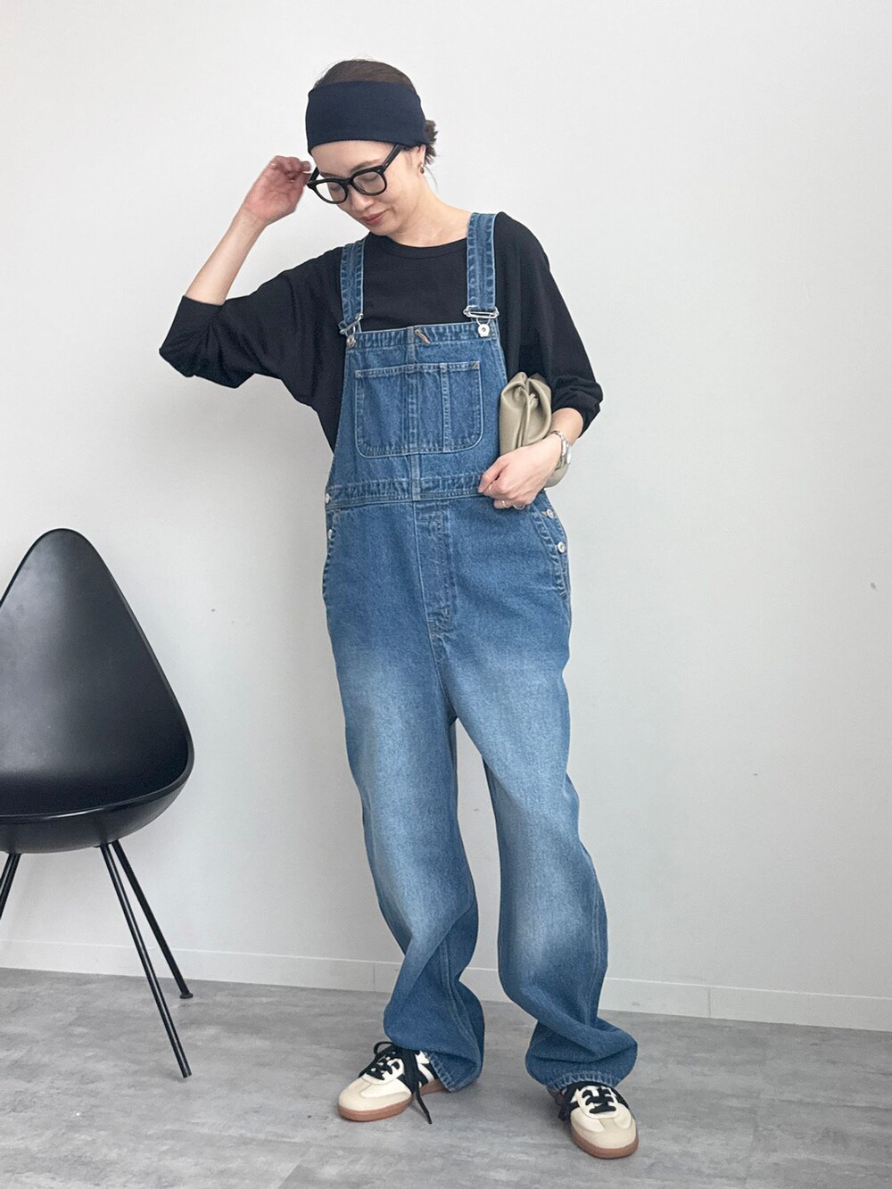 ブラック系のTシャツ/カットソー、ベージュ系のクラッチバッグ、ホワイト系のスニーカーを着用したレディースの冬コーディネートの2枚目の写真