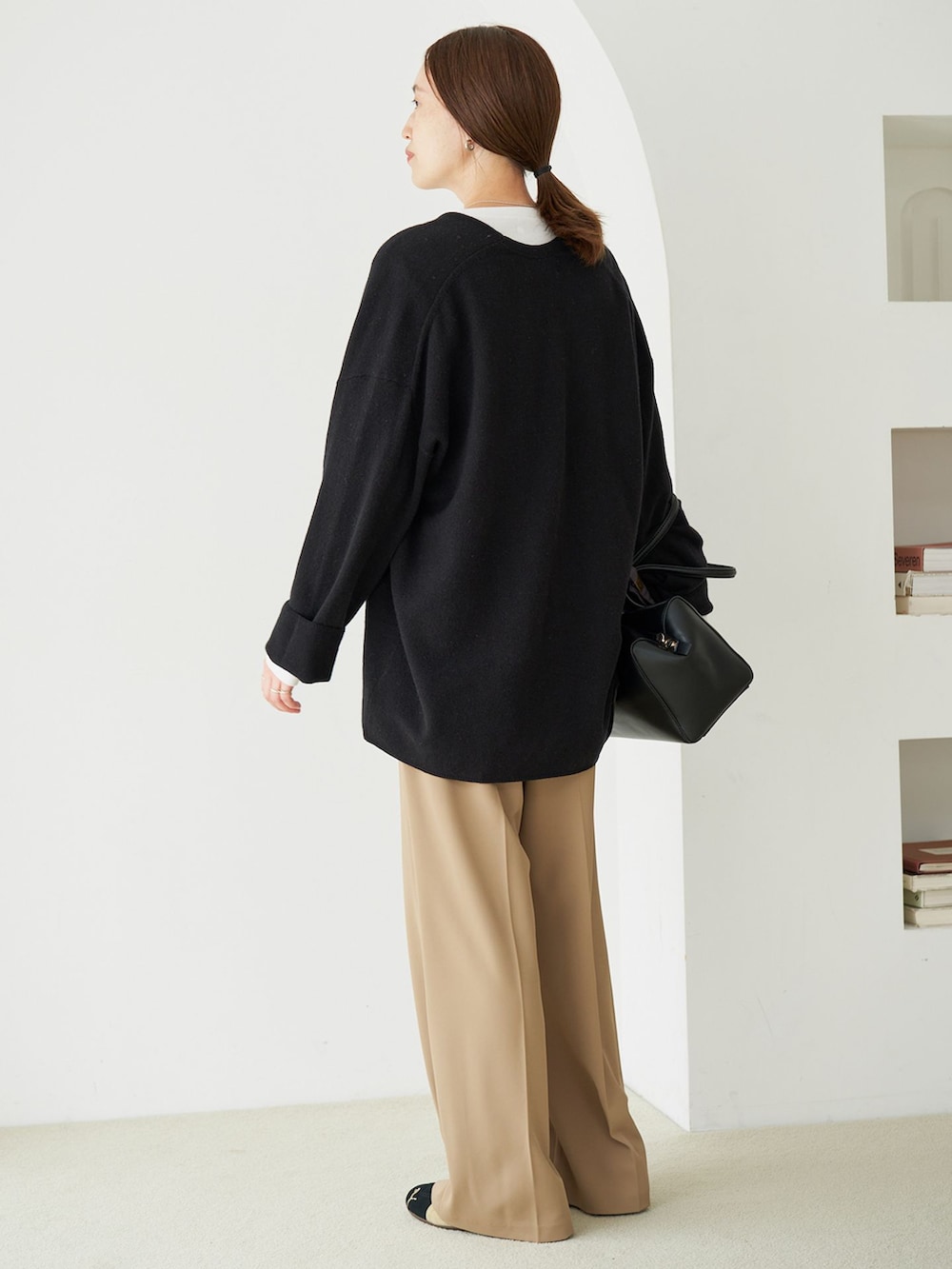 ベージュ系のスラックス、グレー系のTシャツ/カットソー、ブラック系のニット/セーターを着用したレディースの秋コーディネートの2枚目の写真