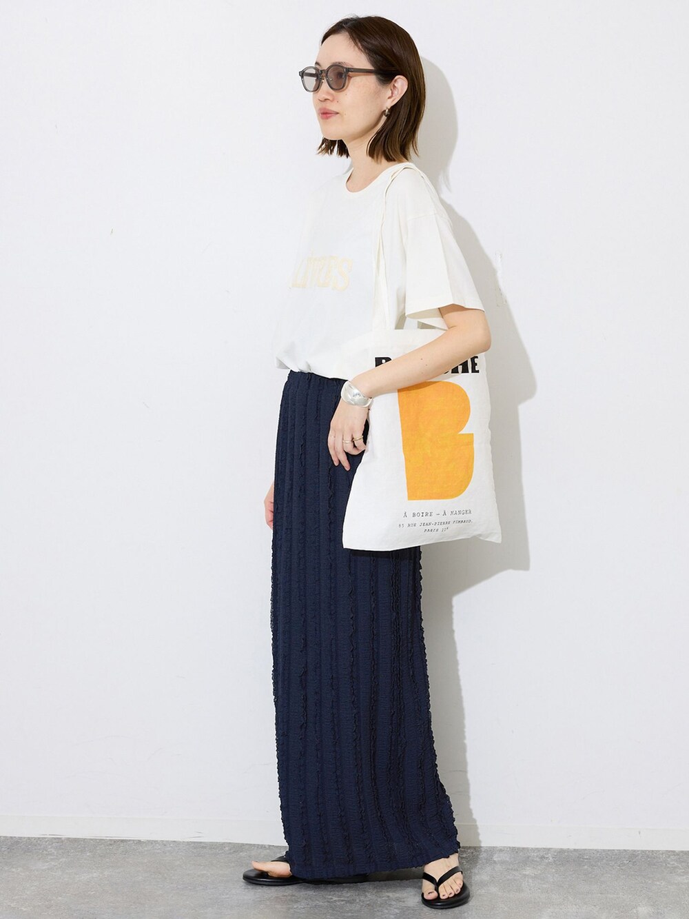 ブルー系のスカート、ホワイト系のTシャツ/カットソー、オレンジ系のトートバッグを着用したレディースの春コーディネートの3枚目の写真