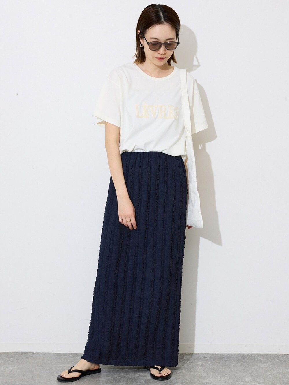 ブルー系のスカート、ホワイト系のTシャツ/カットソー、オレンジ系のトートバッグを着用したレディースの春コーディネートの2枚目の写真