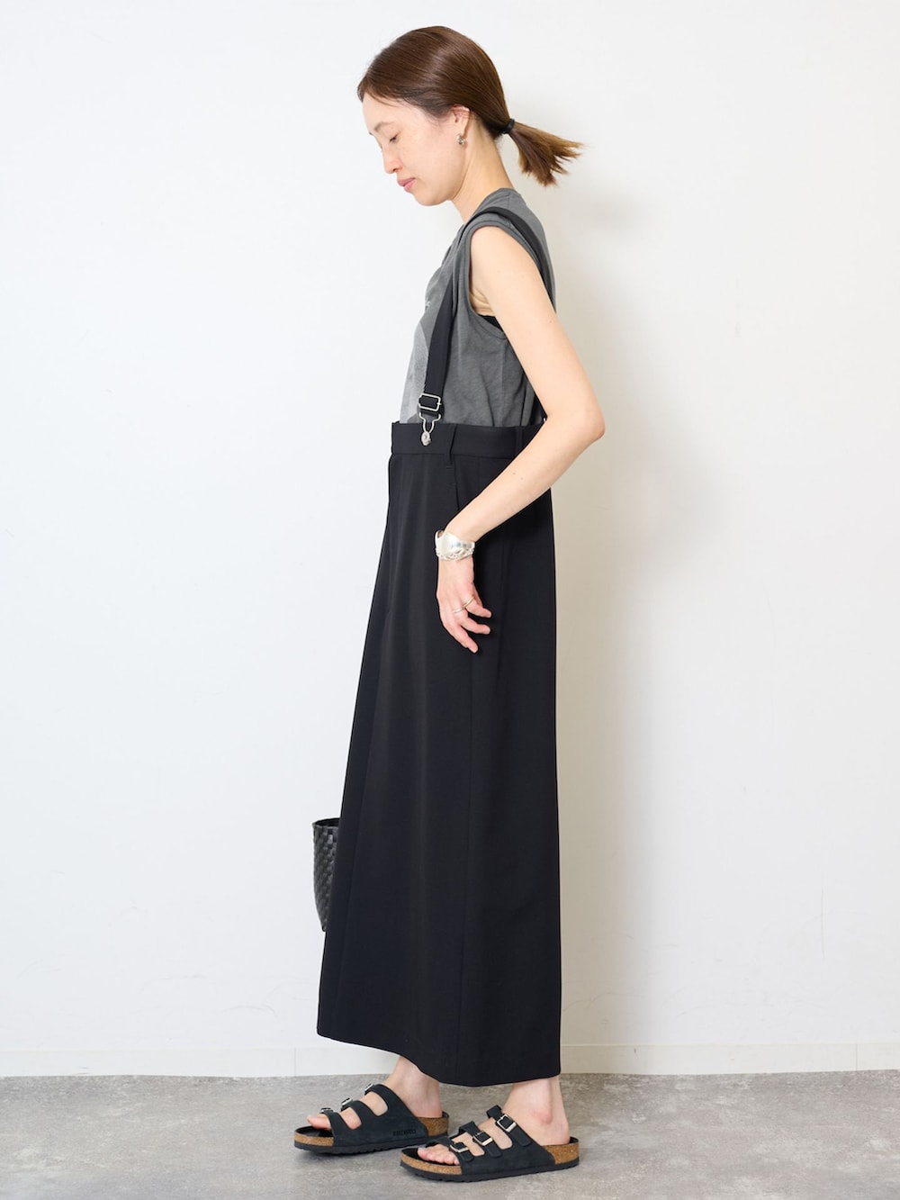 ブラック系のスカート、グレー系のTシャツ/カットソー、ブラック系のかごバッグを着用したレディースの夏コーディネートの2枚目の写真