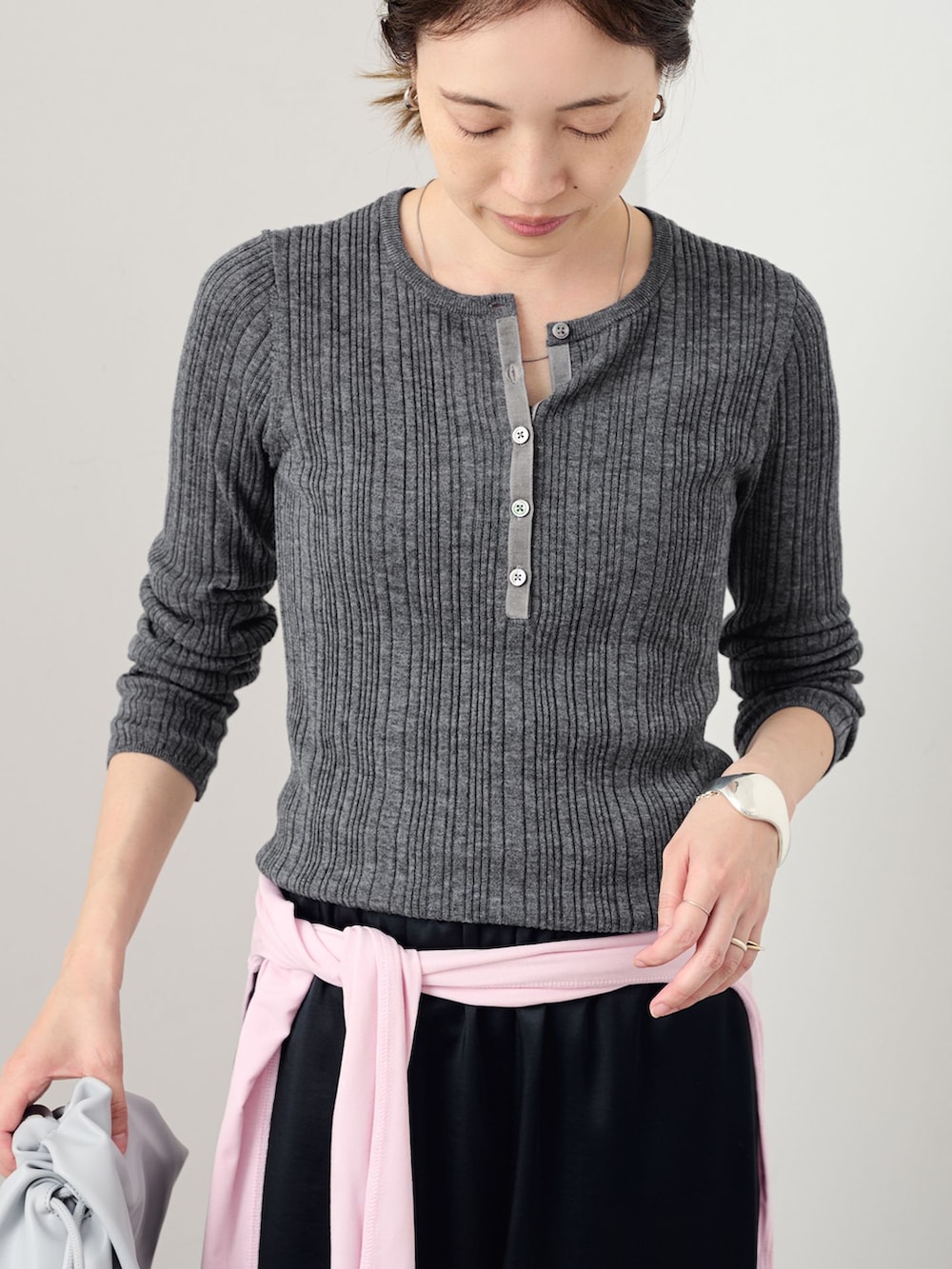 ブラック系のその他パンツ、グレー系のニット/セーター、ブルー系のクラッチバッグを着用したレディースの夏コーディネートの4枚目の写真