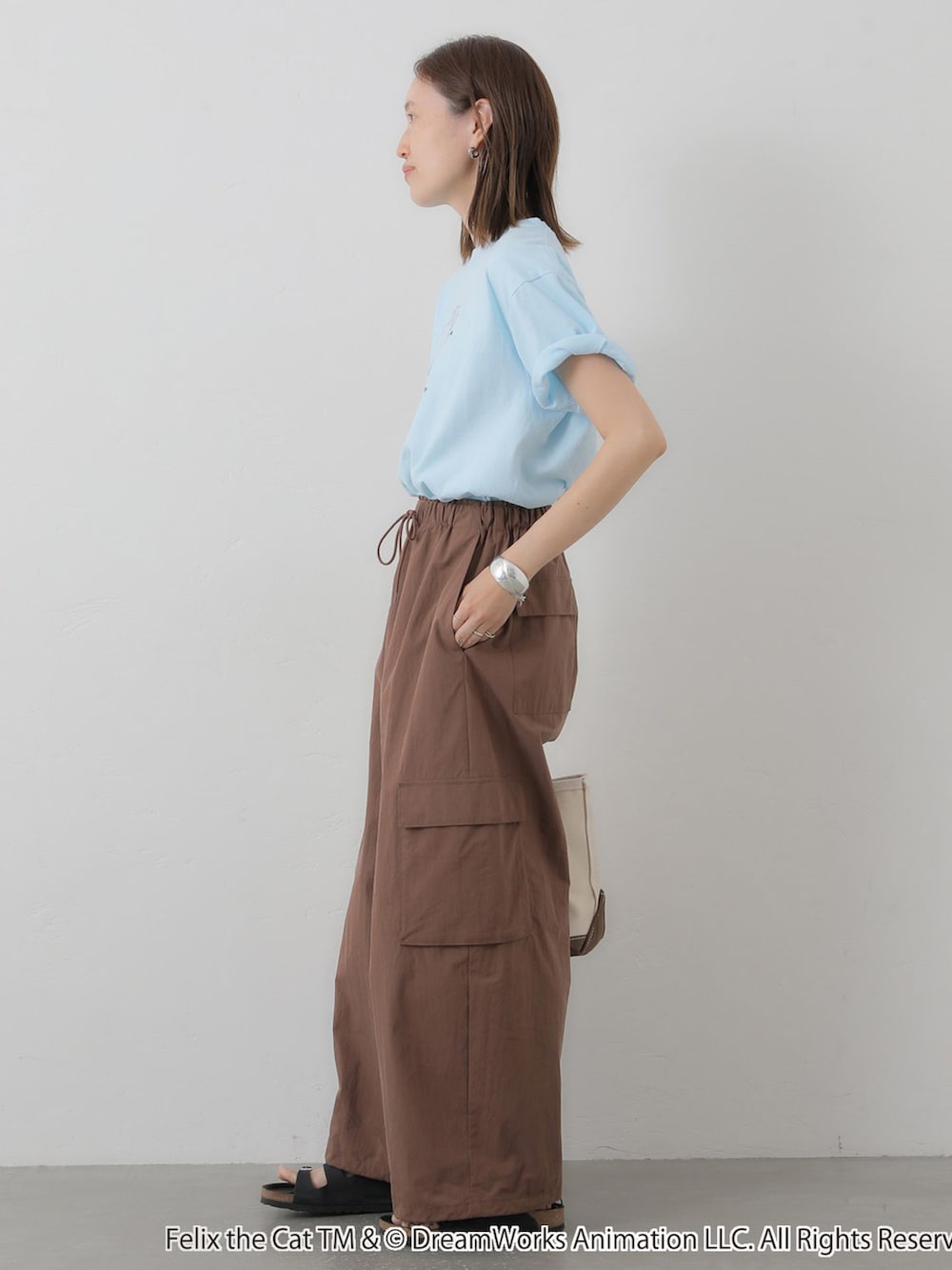ブラウン系のカーゴパンツ、ブルー系のTシャツ/カットソー、ホワイト系のトートバッグを着用したレディースの夏コーディネートの3枚目の写真
