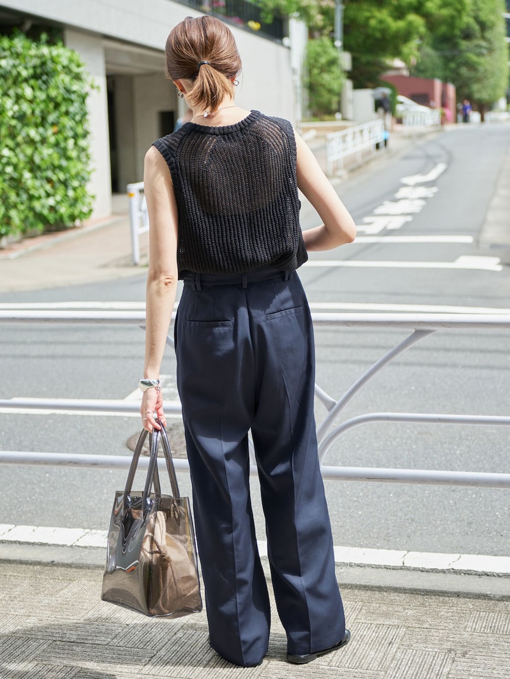 ブルー系のチノパンツ、ブラック系のニット/セーター、ブラック系のトートバッグを着用したレディースの春コーディネートの2枚目の写真