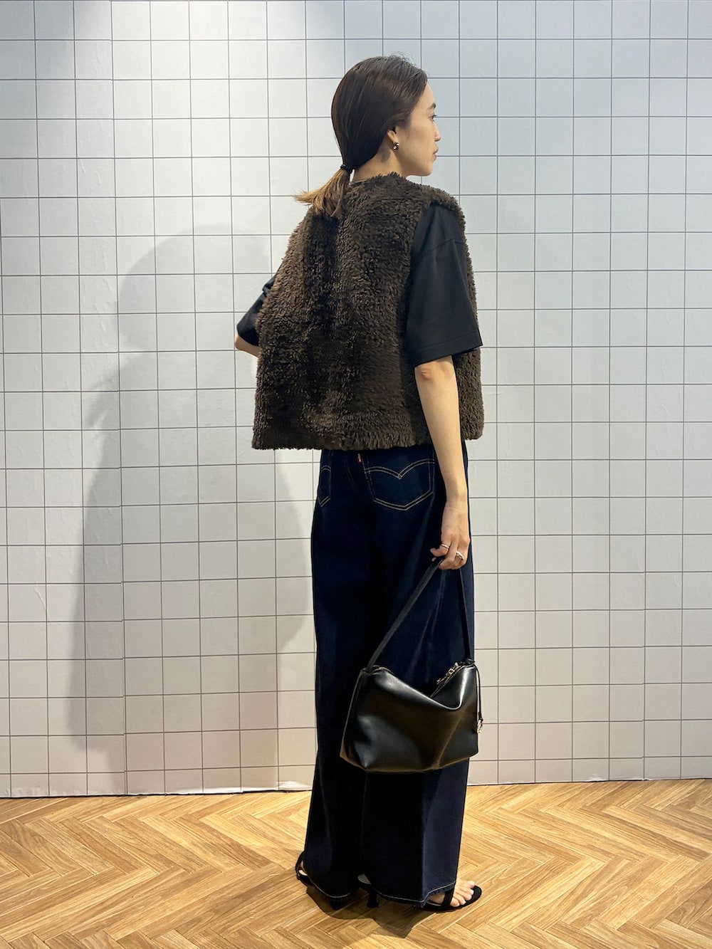 ブルー系のデニムパンツ、ブラック系のTシャツ/カットソー、ブラウン系のベストを着用したレディースの夏コーディネートの6枚目の写真