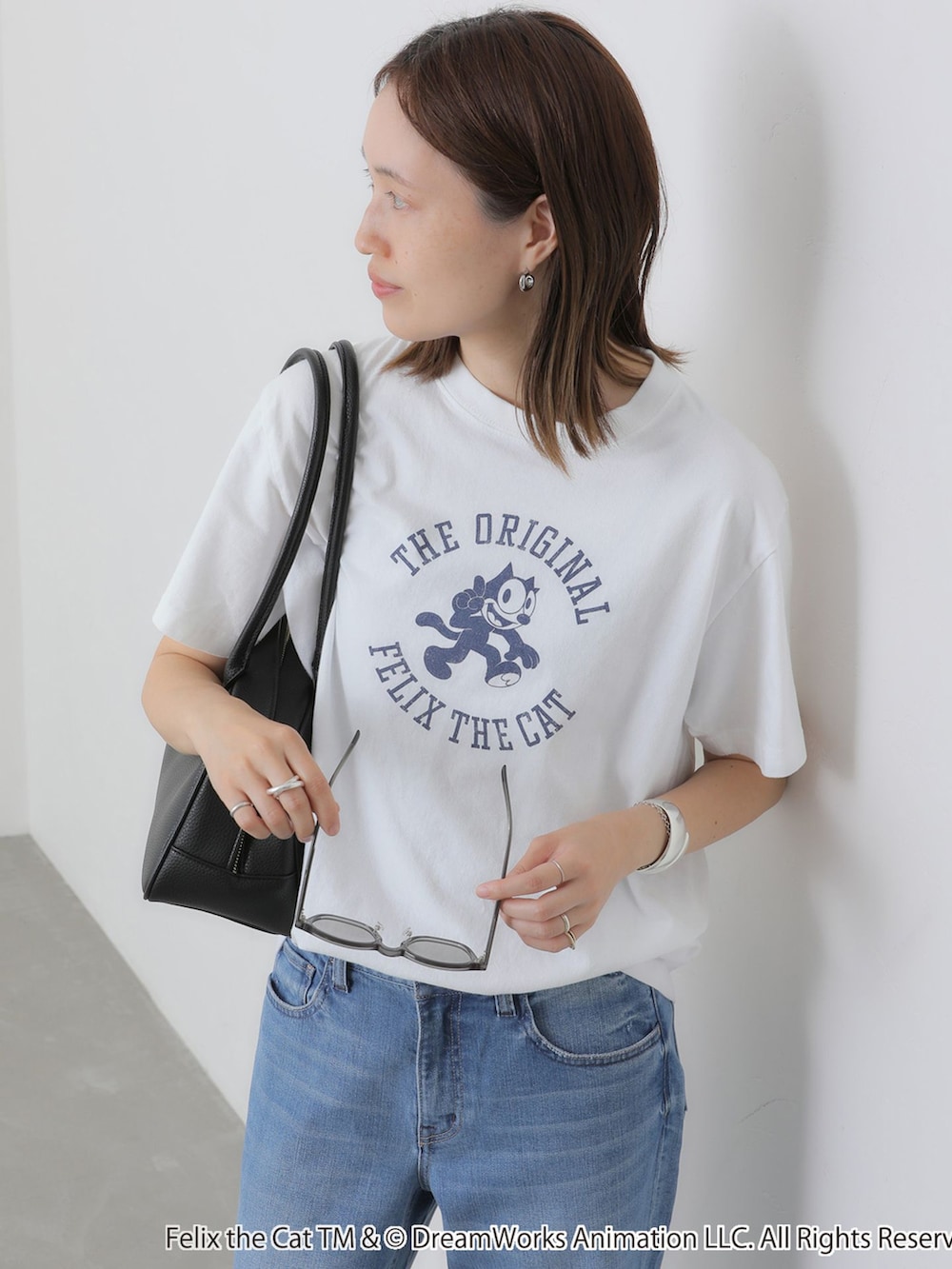 ブルー系のデニムパンツ、ホワイト系のTシャツ/カットソー、ブラック系のボストンバッグを着用したレディースの夏コーディネートの5枚目の写真