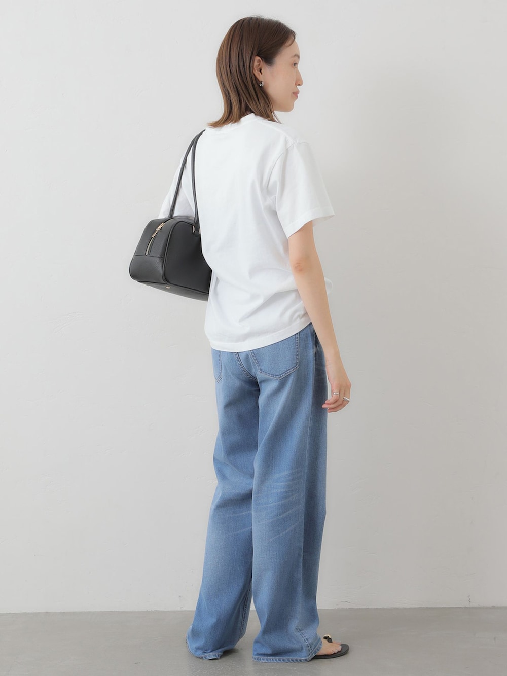 ブルー系のデニムパンツ、ホワイト系のTシャツ/カットソー、ブラック系のボストンバッグを着用したレディースの夏コーディネートの4枚目の写真