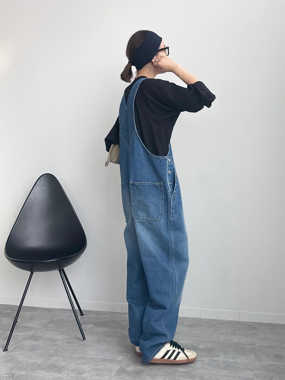 ブラック系のTシャツ/カットソー、ベージュ系のクラッチバッグ、ホワイト系のスニーカーを着用したレディースの冬コーディネートの3枚目の写真