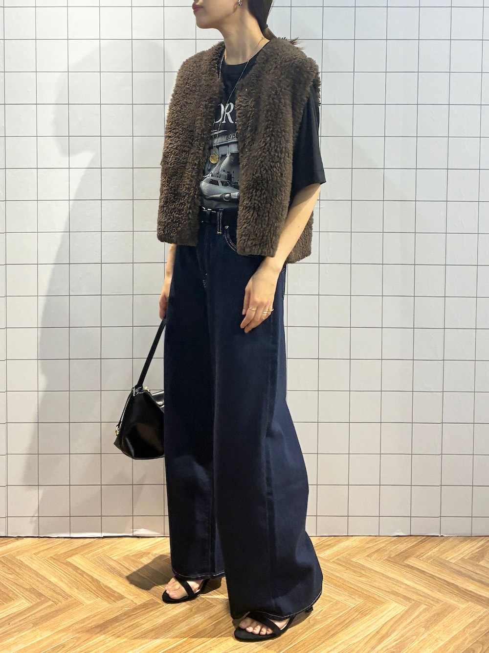 ブルー系のデニムパンツ、ブラック系のTシャツ/カットソー、ブラウン系のベストを着用したレディースの夏コーディネートの4枚目の写真