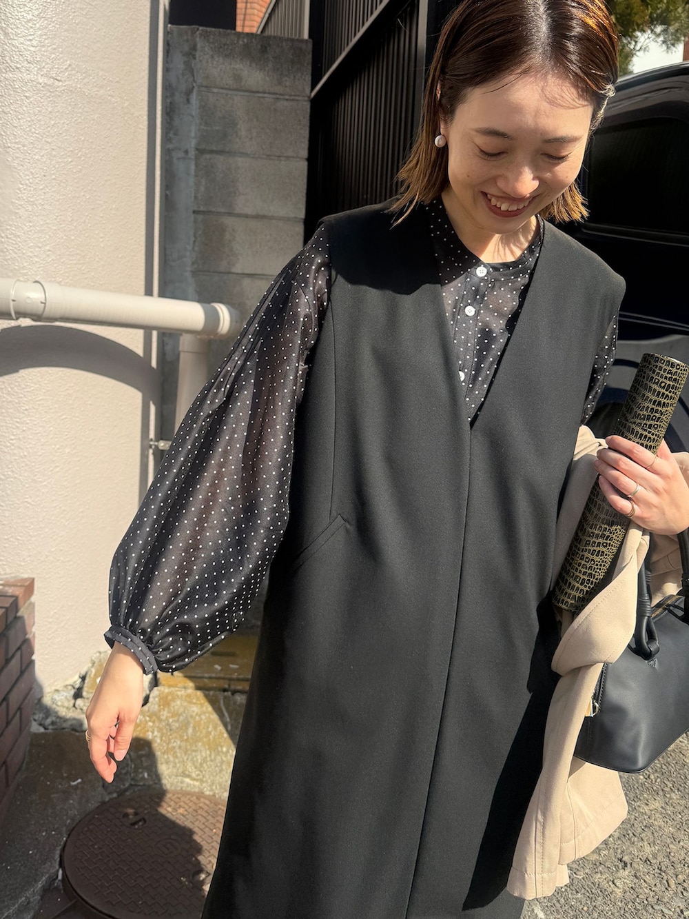 ベージュ系のトレンチコート、ブラック系のワンピース、ブラック系のシャツ/ブラウスを着用したレディースの春コーディネートの5枚目の写真