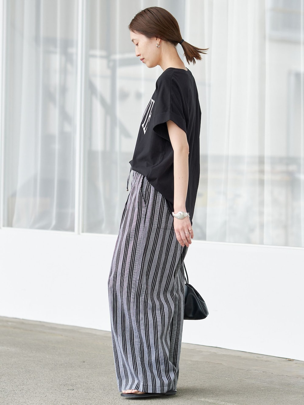 ブラック系のTシャツ/カットソー、ブラック系のクラッチバッグ、ブラック系のサンダルを着用したレディースの夏コーディネートの2枚目の写真