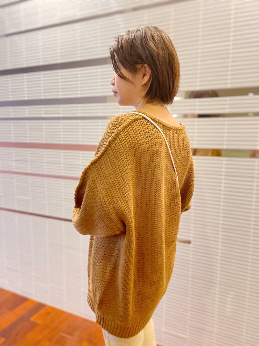 ホワイト系のデニムパンツ、ホワイト系のショルダーバッグ、ブラウン系のニット/セーターを着用したレディースの秋コーディネートの2枚目の写真