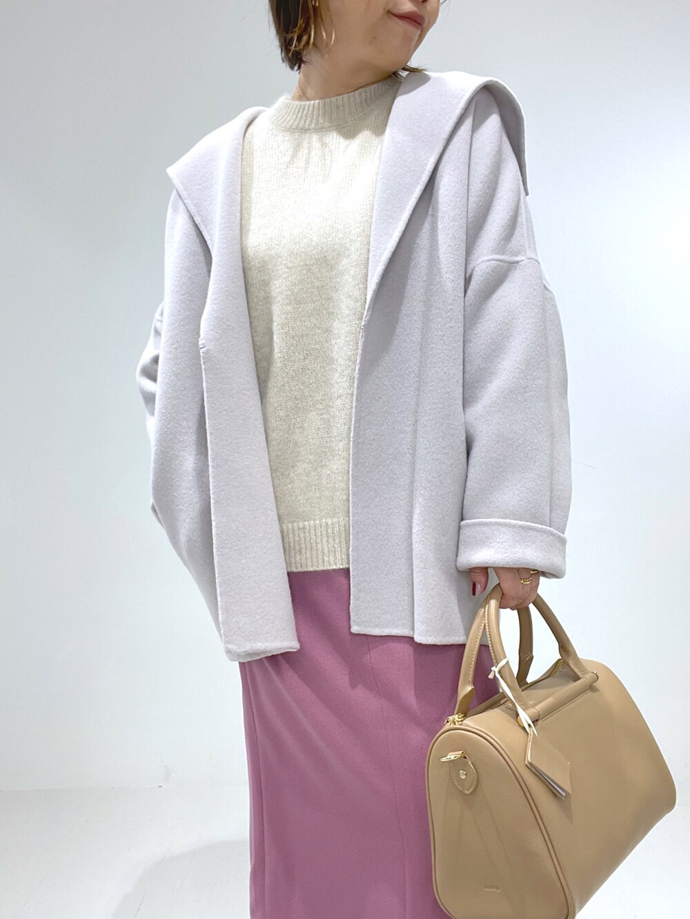 グリーン系のボストンバッグ、ベージュ系のブーツ、ピンク系のスカートを着用したレディースの冬コーディネートの2枚目の写真