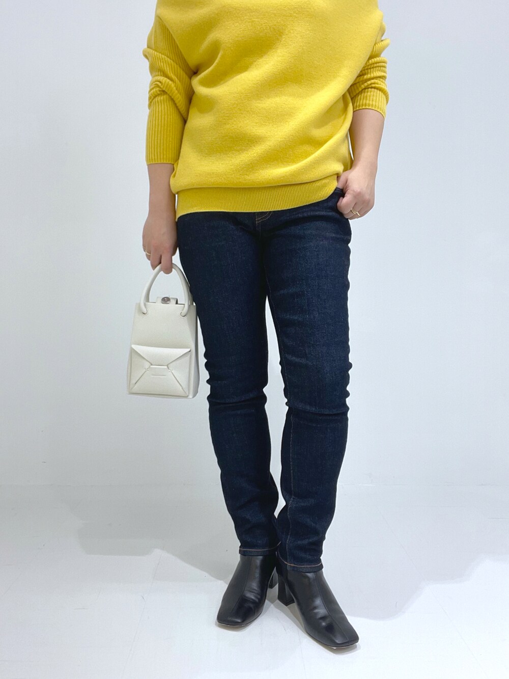 ブラック系のブーツ、イエロー系のトートバッグ、イエロー系のニット/セーターを着用したレディースの秋コーディネートの3枚目の写真